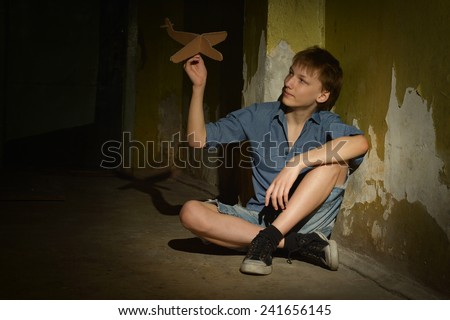 Lonely little boy in a dark cellar with toy plane