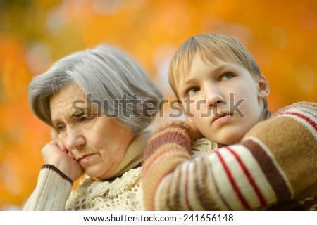 Sad Grandmother with boy in the autumn park