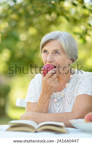 Portrait of a beautiful middle-aged woman outdoors at the table reading a book
