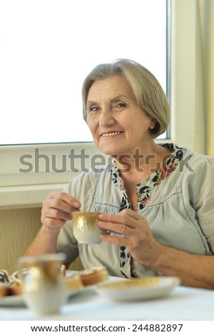 Beautiful elderly woman at home with cup of tea