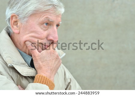 Portrait of cold senior man on grey background