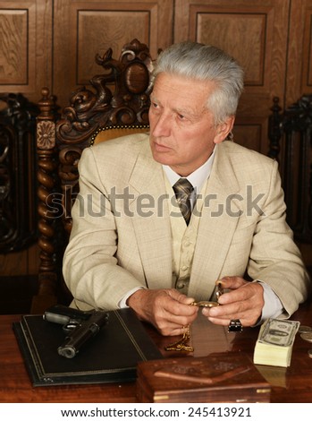 Mature male mafia boss on the table with gun