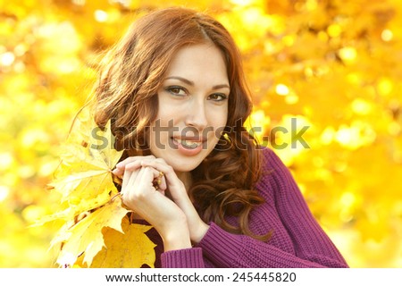 young woman with leaves posing in autumn park