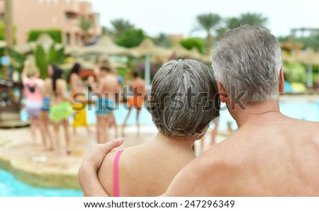Back view of Elderly couple standing by pool at hotel resort