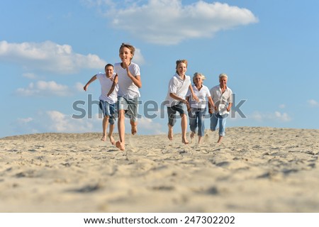 Big happy family running barefoot in the sand in the summer