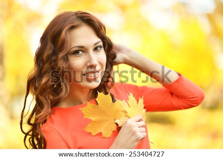 Beautiful young woman with leaves posing in autumn park