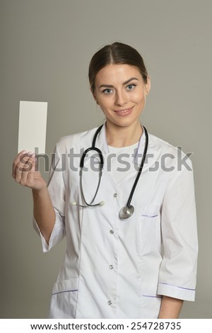 Female doctor with white list, standing on grey background