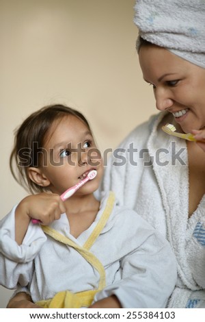 Mom and her little daughter brushing their teeth