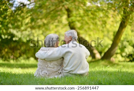 Happy elderly couple sitting in autumn park