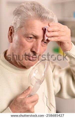 Close-up portrait of an elder man making inhalation