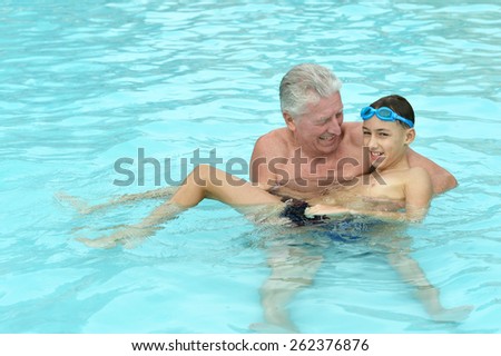 Portrait of a happy grandfather with grandson in swimming pool
