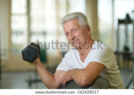 Elderly man in a gym. exercising with dumbbell