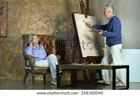 Portrait of beautiful elderly couple painting with easel