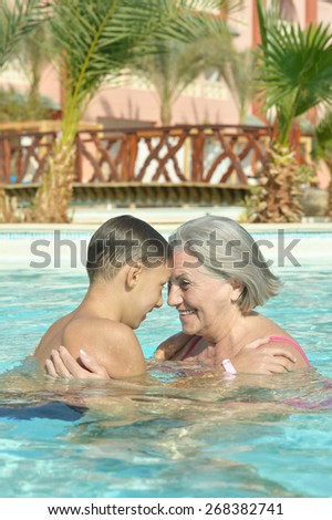 Happy smiling grandma and grandson in blue pool water