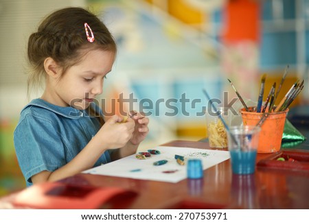 Little girl drawing with paints at home