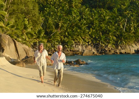 Elderly couple running on the beach near the sea