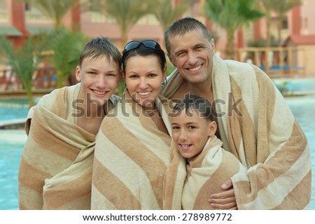 Happy family covered with towels near swimming pool