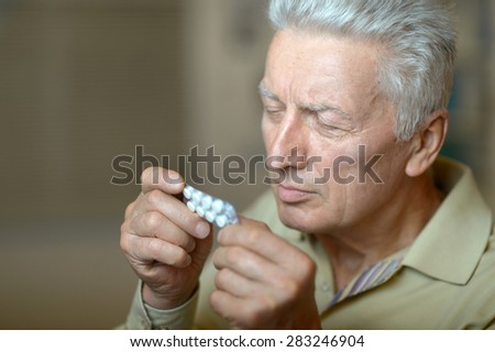 elderly ill man with pills in hand