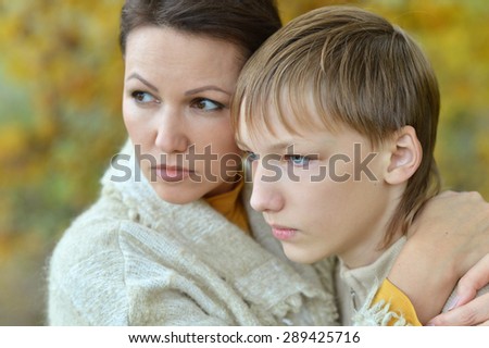Sad mother with son on a walk in autumn park