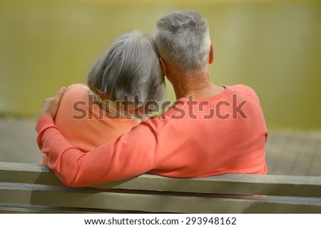 Happy elderly couple sitting on bench in autumn park