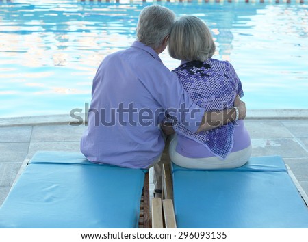 Happy Elderly couple resting near pool water together at vacation
