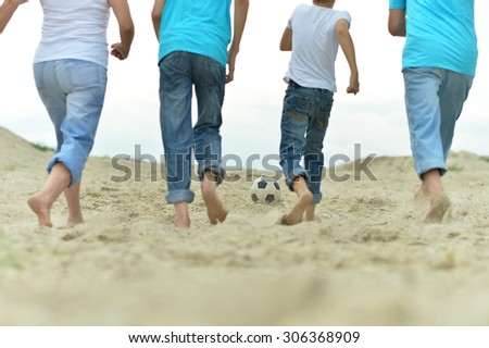 Big Family playing football on a beach in summer day