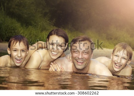 Beautiful family swims in the river in summer