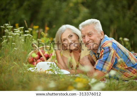 Happy elder couple resting on grass at nature