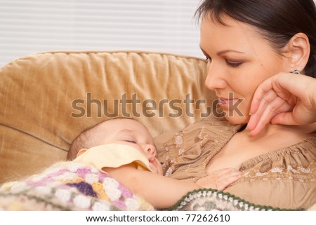 happy mom with her sleeping baby on sofa