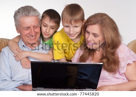 happy grandparents and grandsons with a laptop