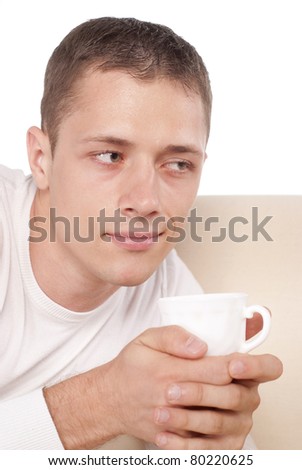 portrait of a pretty guy with cup lying on sofa