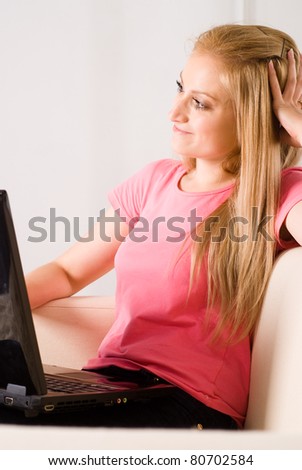girl in a pink sitting on sofa with laptop