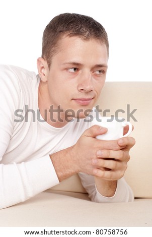 portrait of a pretty guy with cup lying on sofa