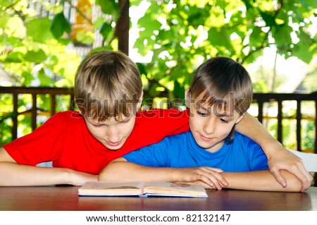 two boys reading a book at nature