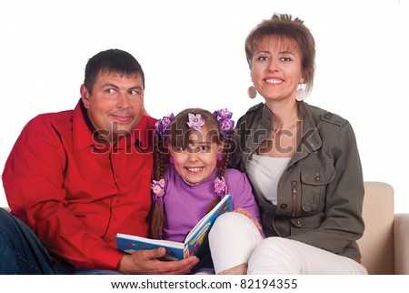 daughter reads with parents on a sofa