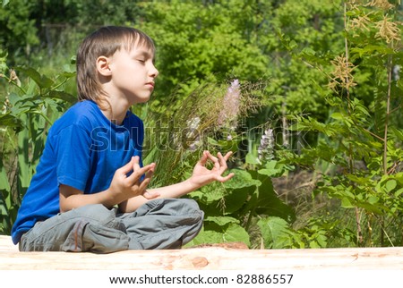cute young boy meditates at the  nature