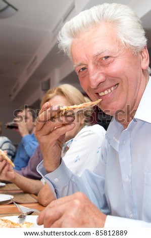 portrait of a cute old man eating pizza