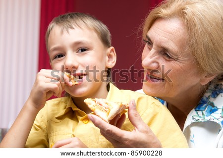 portrait of a cute granny and grandson eating pizza