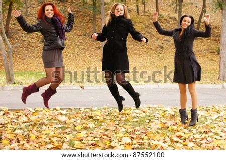 three happy girls jumping at autumn park