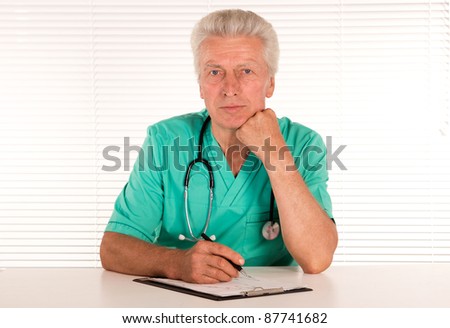 portrait of a cute senior doctor at table