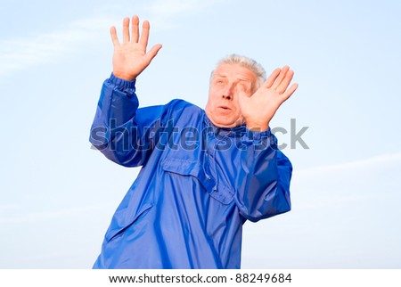 cute old man in blue posing at sky