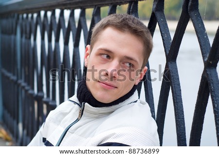portrait of a pretty guy sitting at fence