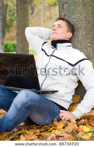 portrait of a pretty guy sitting at autumn park