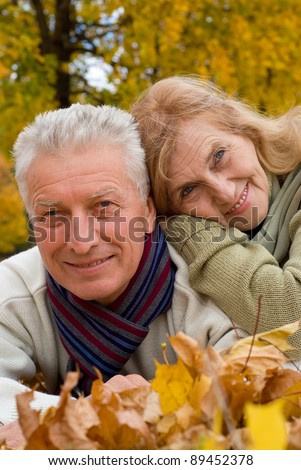 cute old couple lying on autumn leaves