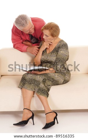 portrait of a cute old woman and man reading at couch