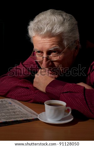 old guy with newspaper and tea at table