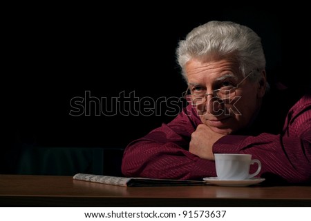 old guy with newspaper and tea at table