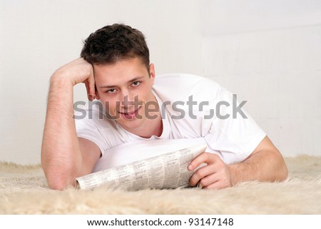cute young man with newspaper at carpet