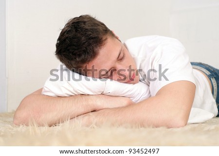 cute young man with cushion at carpet