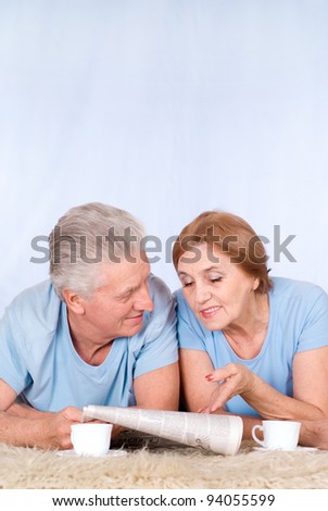 cute old couple lying and reading newspaper